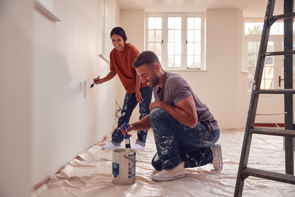 Couple interior Painting Test Squares On Wall As They Decorate Room In New Home Together