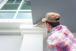 Home or house exterior painting work consist of painter man and bristles brush at crown molding at top column