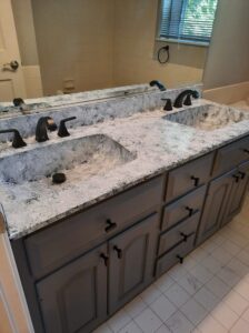 Cabinet Painting. DIY Affordable Bathroom Remodel. The bathroom was transformed by painting the cabinets gray, installing a countertop kit on the counter.