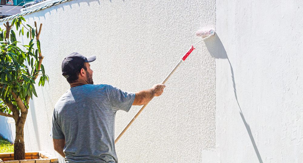 Residential Painting. Painter man painting a wall on an external wall of a residence .