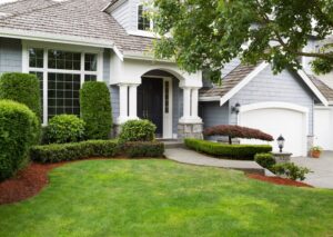 Painting Services. Newly painted exterior of a home during summertime with green grass and flower beds.