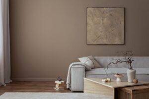 Residential Painting. Warm and cozy living room interior with mock up poster frame, painting, beige sofa, travertine coffee table, slippers, bowl with nuts, plaid, pillow and personal accessories. Home decor. Template.