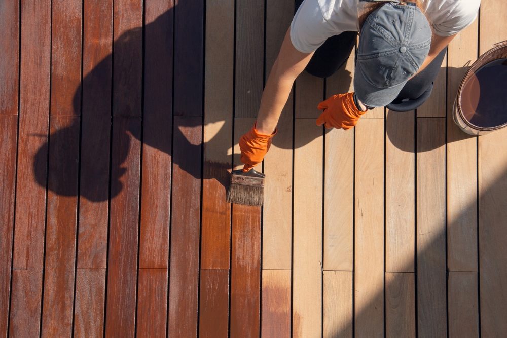 Why Islanders Choice Is #1 for Deck Painting in Victoria. Exterior wood deck painting, overhead worker applying protective deck stain.